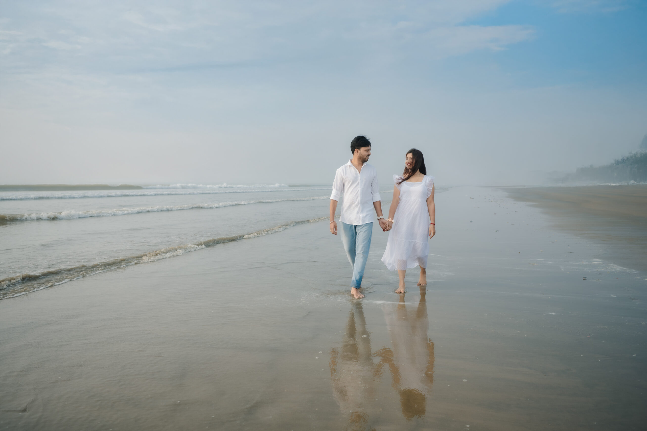 Couple holding hands while walking along a quiet beach