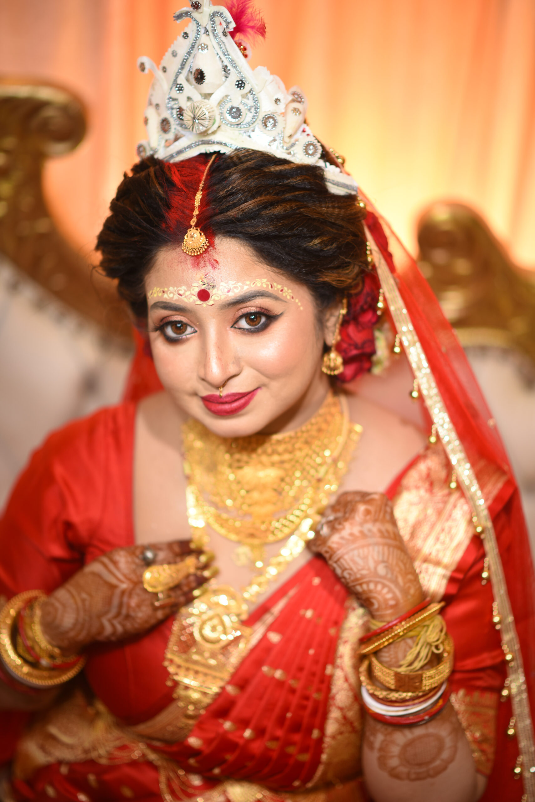 Close portrait of a Bengali bride wearing gold jewellery and a red sari